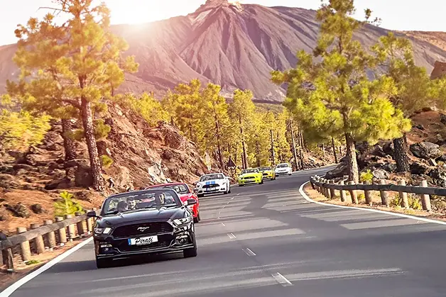 Ford Mustang convertibles driving through Teide National Park in Tenerife with Mount Teide in the background.